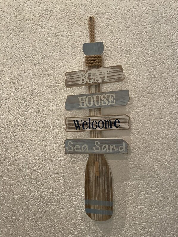 A wooden sign with the words 'Boat House Welcome Sea Sand' mounted on a wall. - City Müllers Apartment (Bremerhaven)