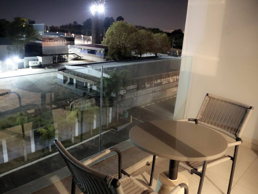 A balcony with a glass railing, a table, and two chairs.