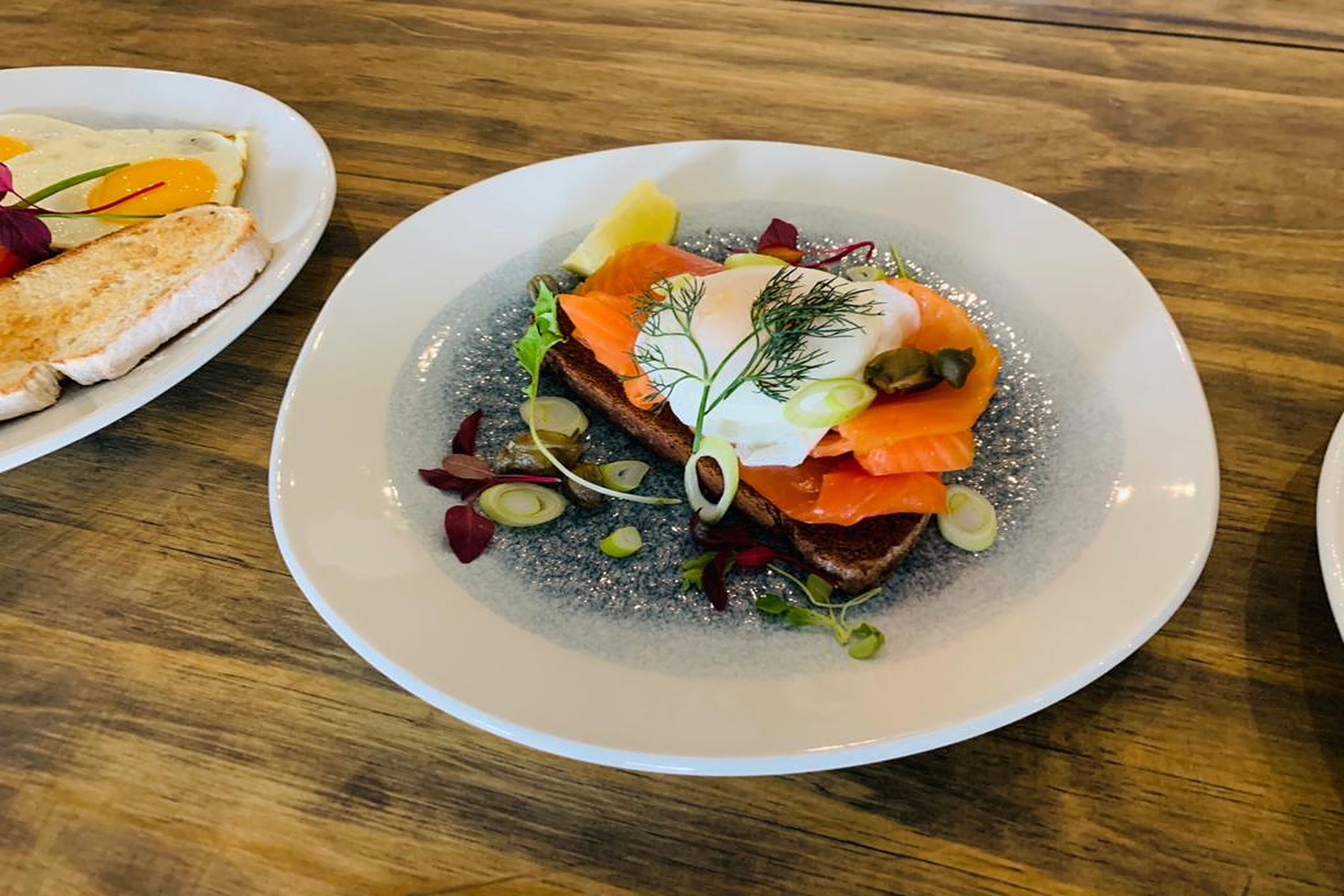 A plate of food with salmon, greens, and a dollop of cream.