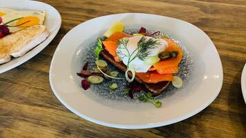 A plate of food with salmon, greens, and a dollop of cream.