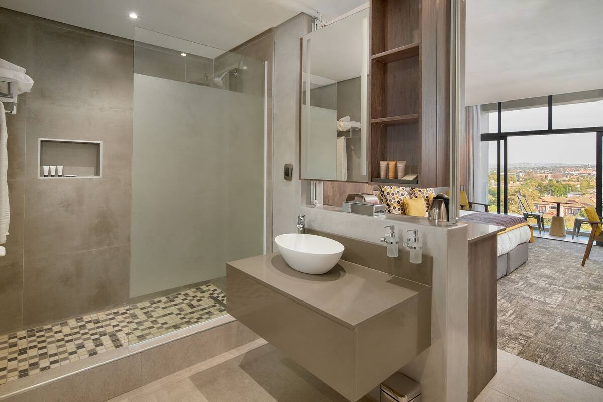 A modern bathroom with a large mirror, a white sink, and a shower area.