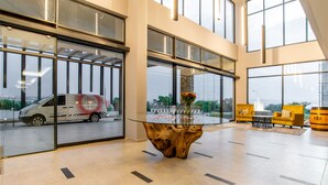 Un vestíbulo espacioso con una mesa de vidrio, muebles modernos y grandes ventanales con vistas al exterior.