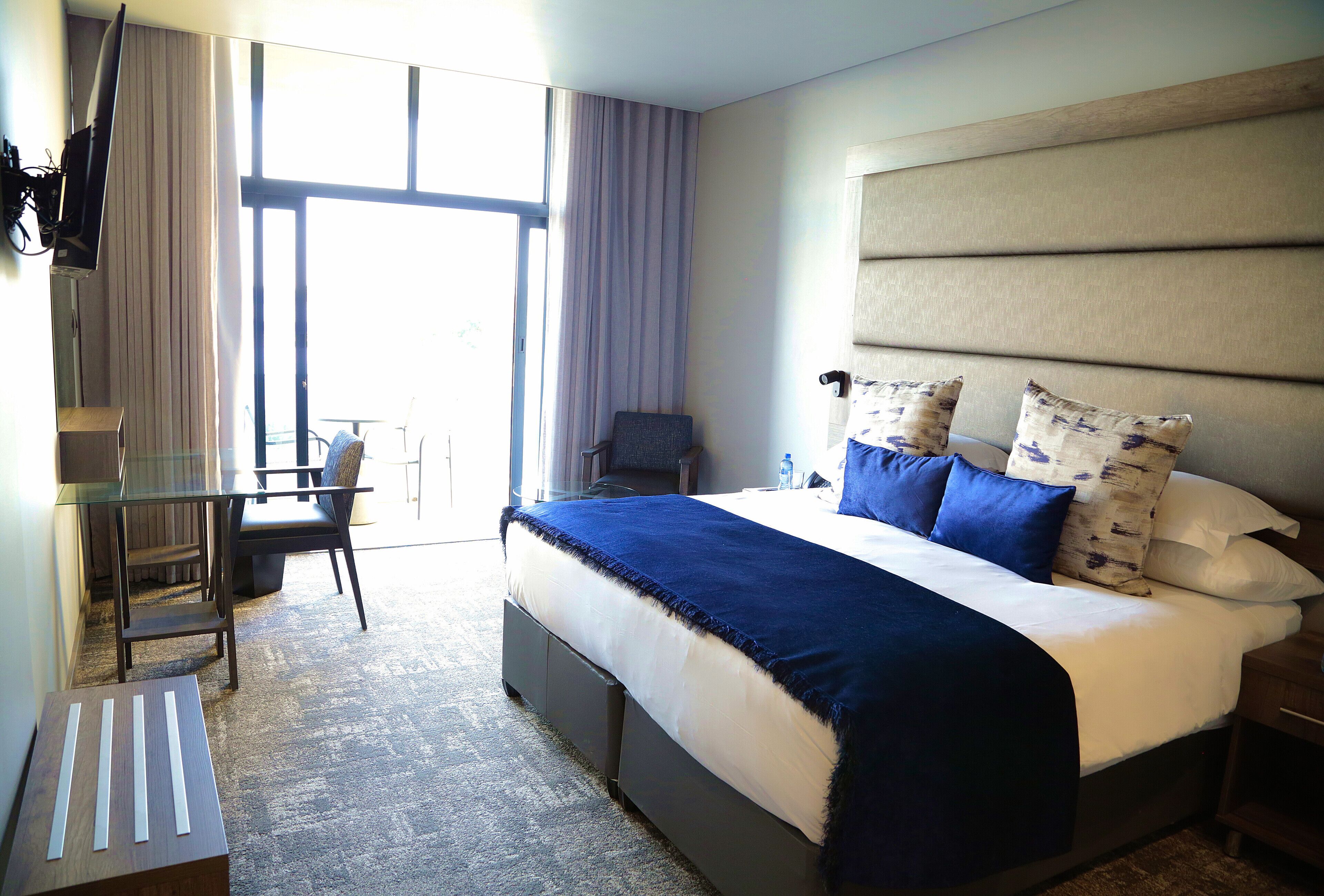 A hotel room with a large bed, a desk, and a chair.