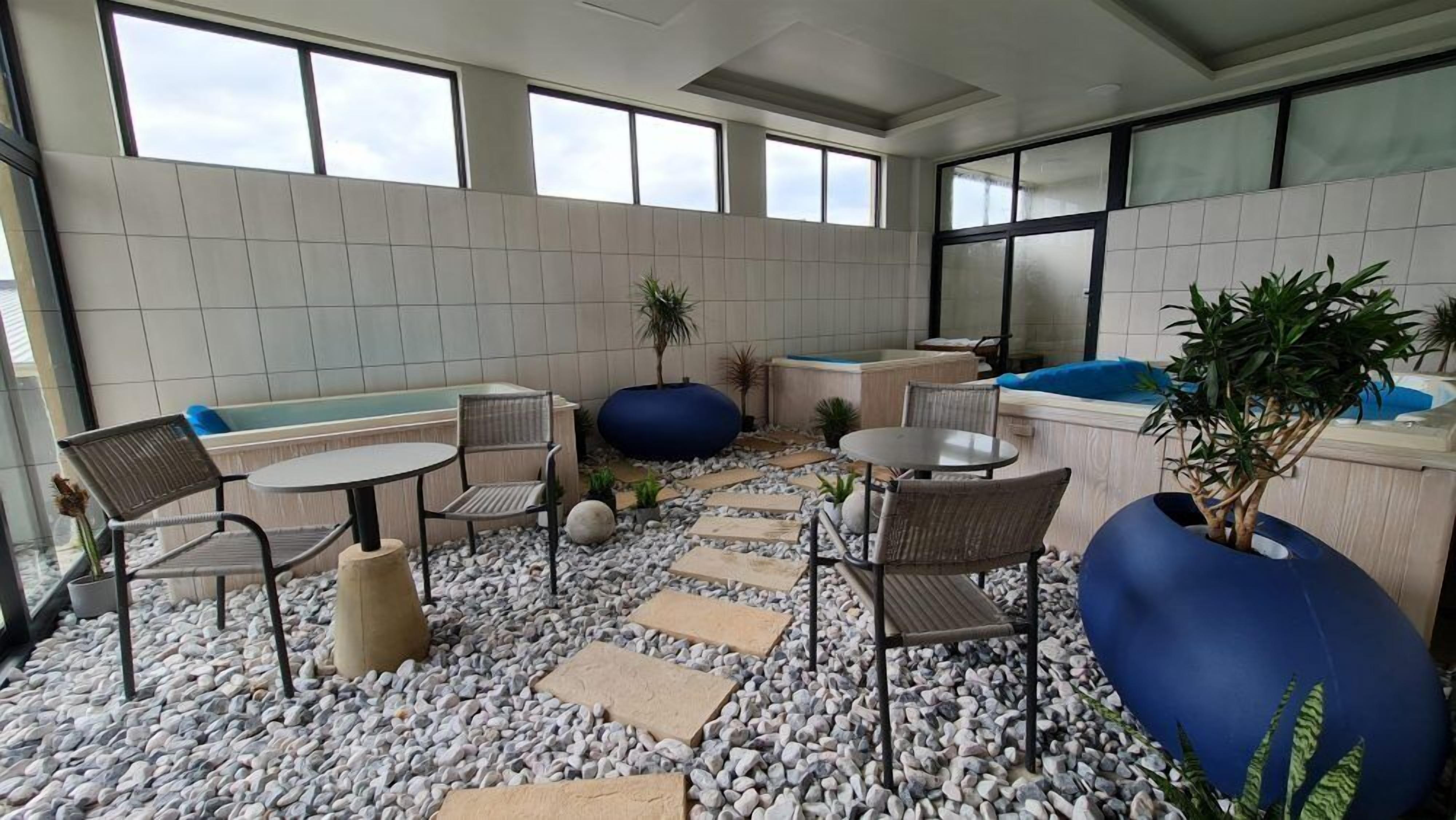 Een moderne, overdekte ontspanningsruimte met een zithoek, een kleine tafel en een bad.