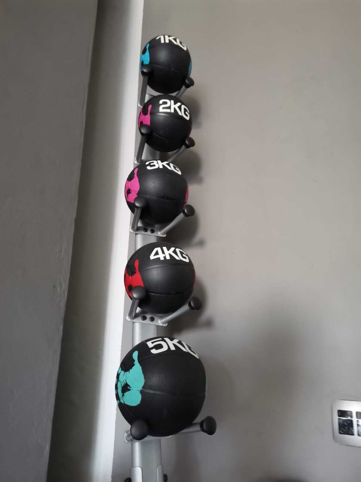 Un support mural pour balles d'exercice, avec des balles allant de 1 kg à 5 kg.