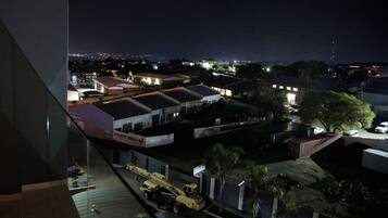 Vue nocturne d’une zone commerciale avec des immeubles, une grue et une enseigne indiquant « AJ AUTO BODY Repairs ».