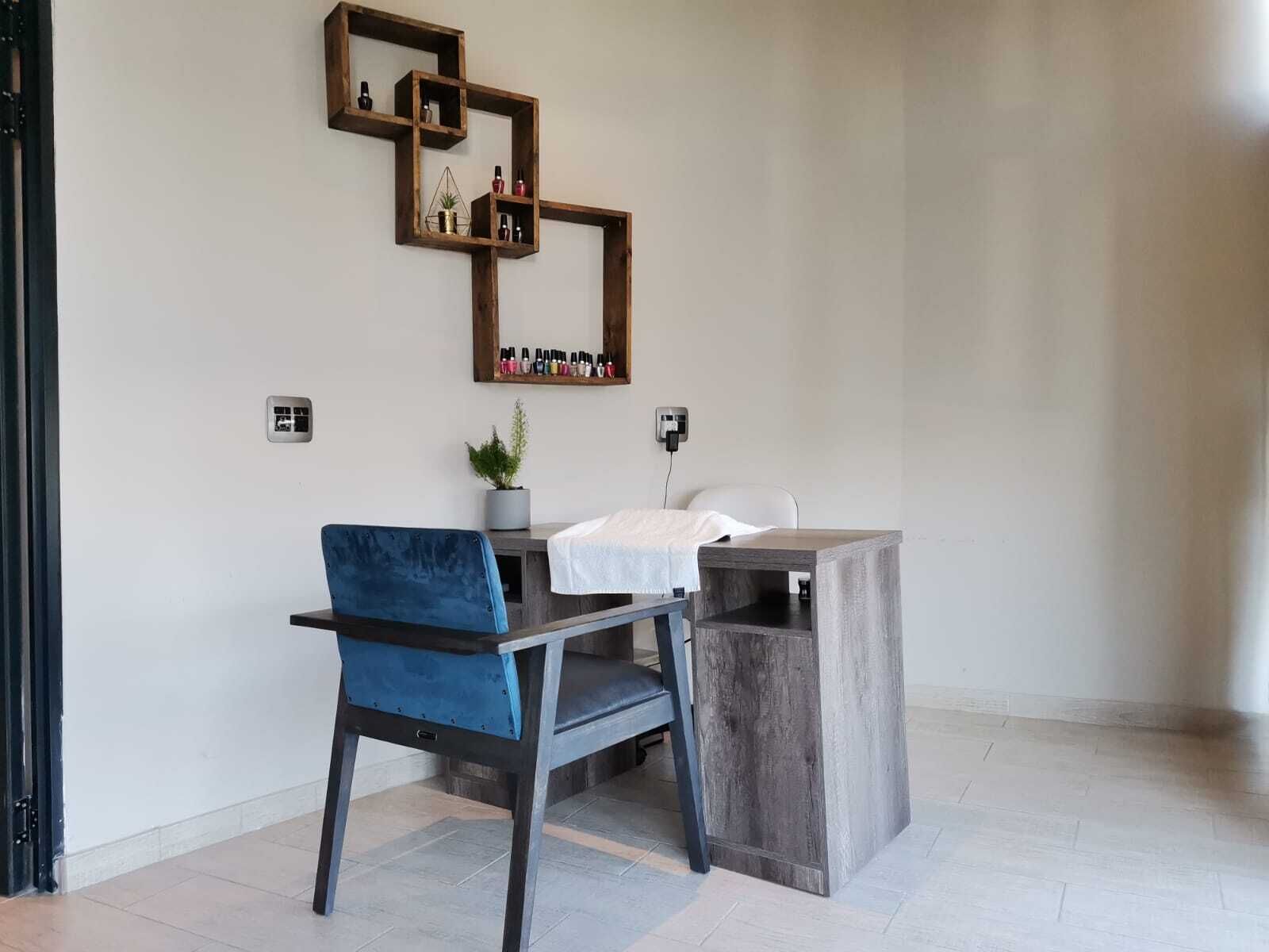A modern room with a desk, chair, and a wall-mounted shelf with various items.