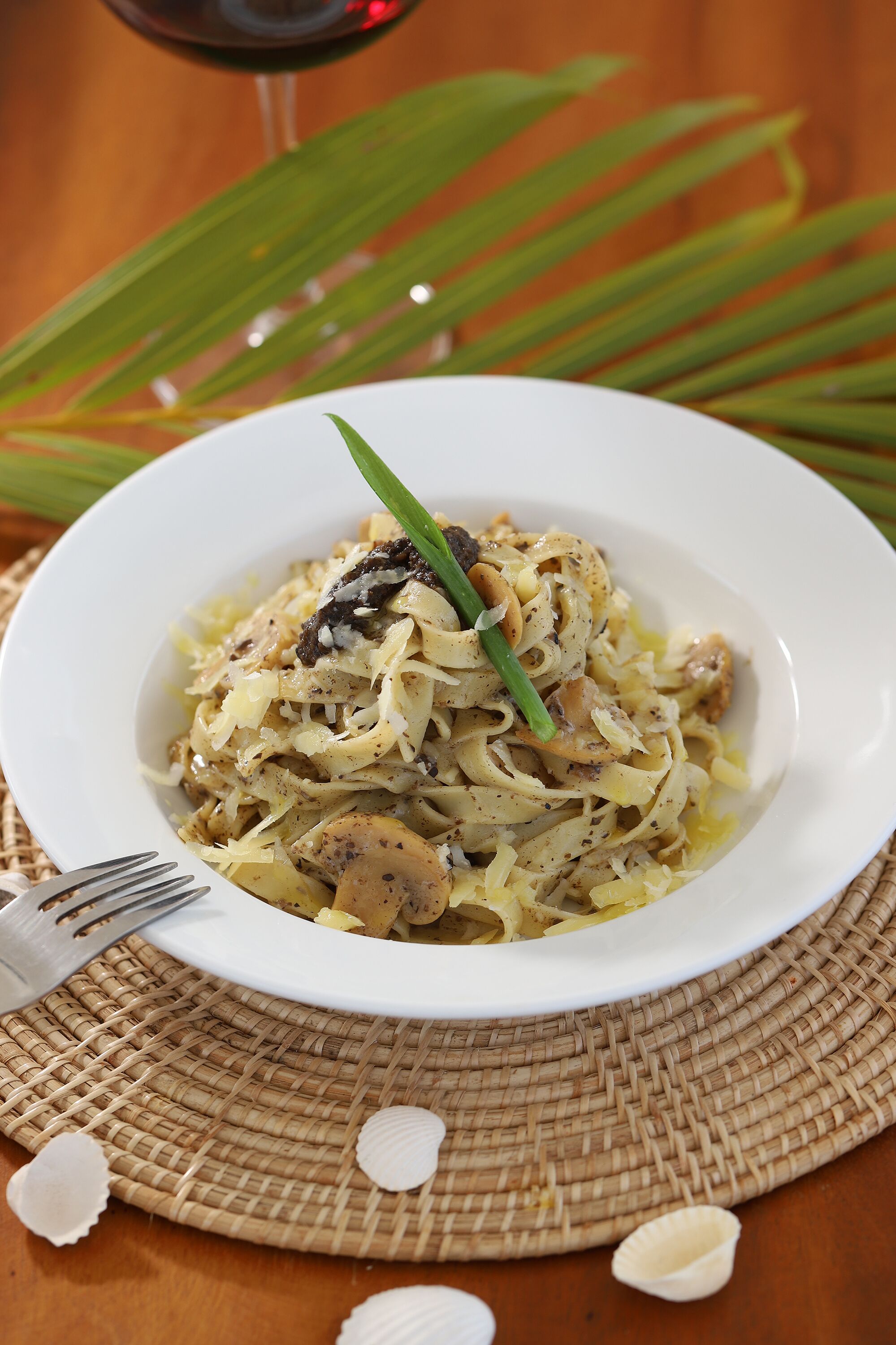 Un plato de pasta con un tenedor al lado, sobre un camino de mesa tejido.