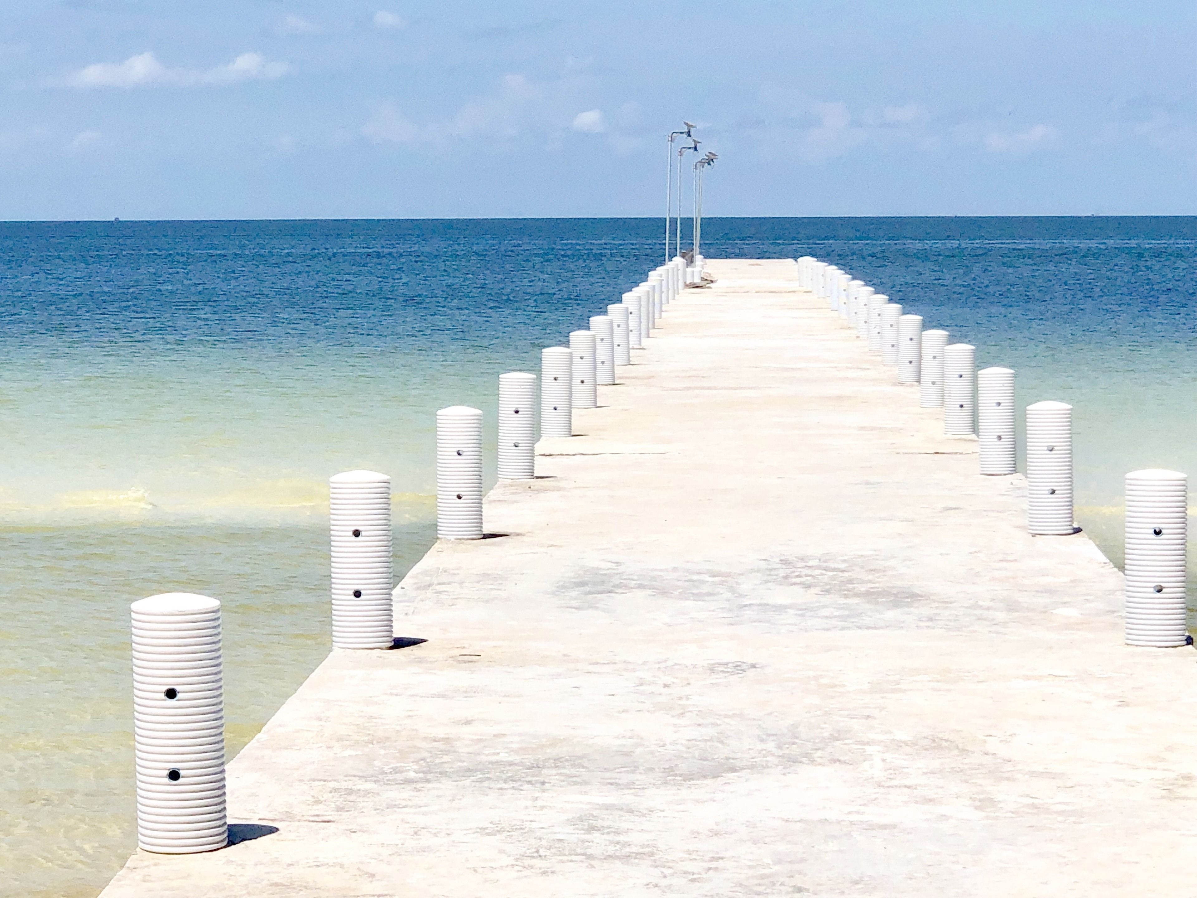 Un muelle largo que se adentra en el mar con pilares blancos espaciados.