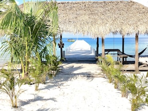 A beach pathway leading to a thatched structure with a view of the sea.
