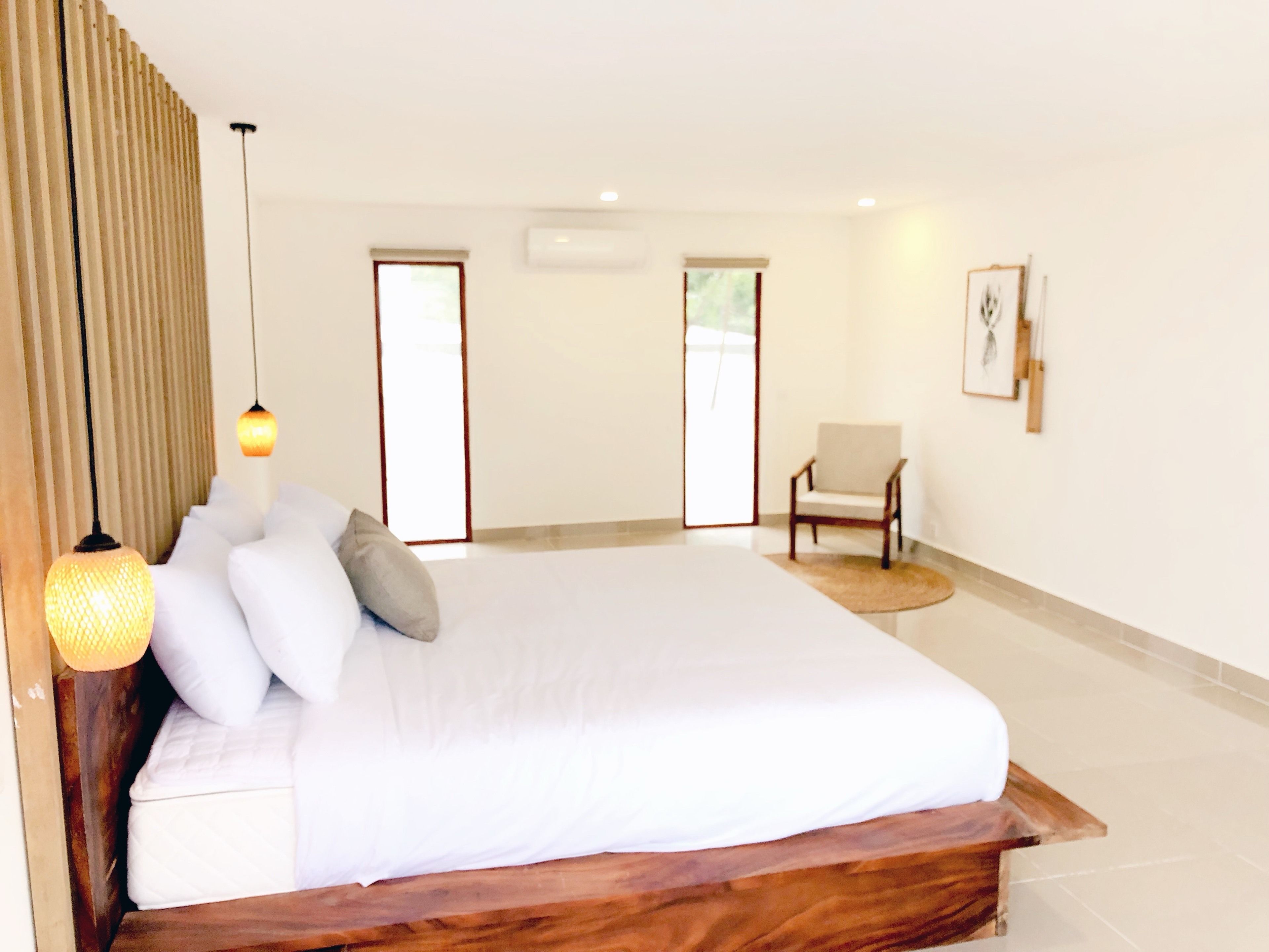 A bedroom with a large bed, a chair, and a round rug.