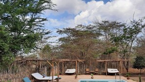 Un espace piscine doté de chaises longues et d’une structure en forme de pergola.