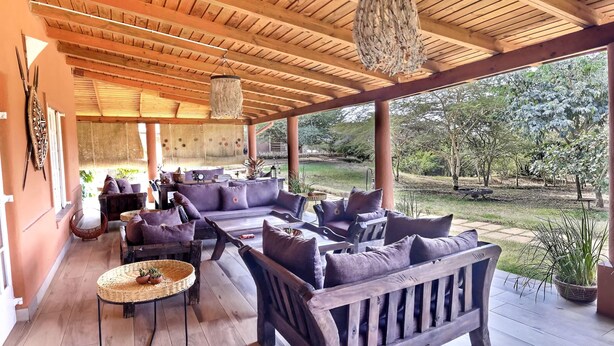 Un espace extérieur abrité, aménagé avec du mobilier en bois et offrant une vue sur le jardin.