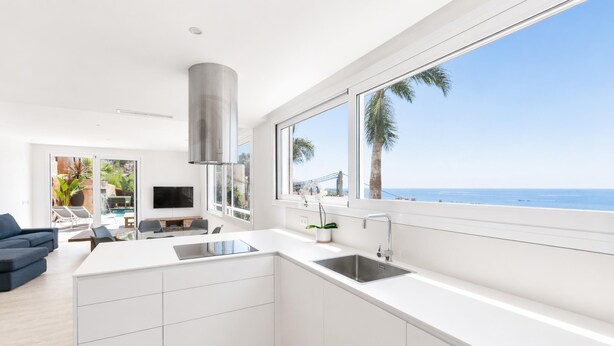 A modern kitchen with a large island, white cabinetry, and a view of the ocean. - Luxury villa with private pool and sea view (ANCLA MAR nº5) (Roses)