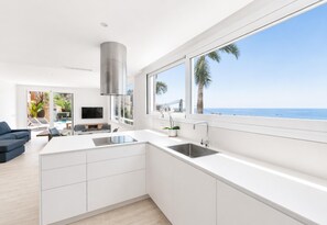 A modern kitchen with a large island, white cabinetry, and a view of the ocean.