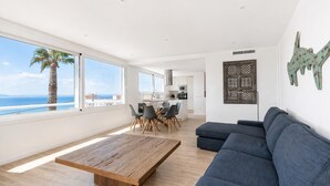 A modern living room with a wooden coffee table, a dark blue sofa, and a view of the sea through large windows. - Luxury villa with private pool and sea view (ANCLA MAR nº5) (Roses)