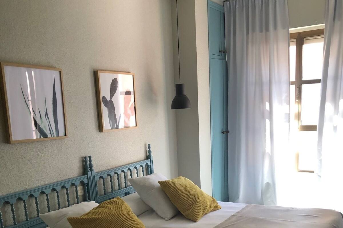 Een hotelkamer met twee bedden, een plafondventilator en kunstwerken aan de muur.