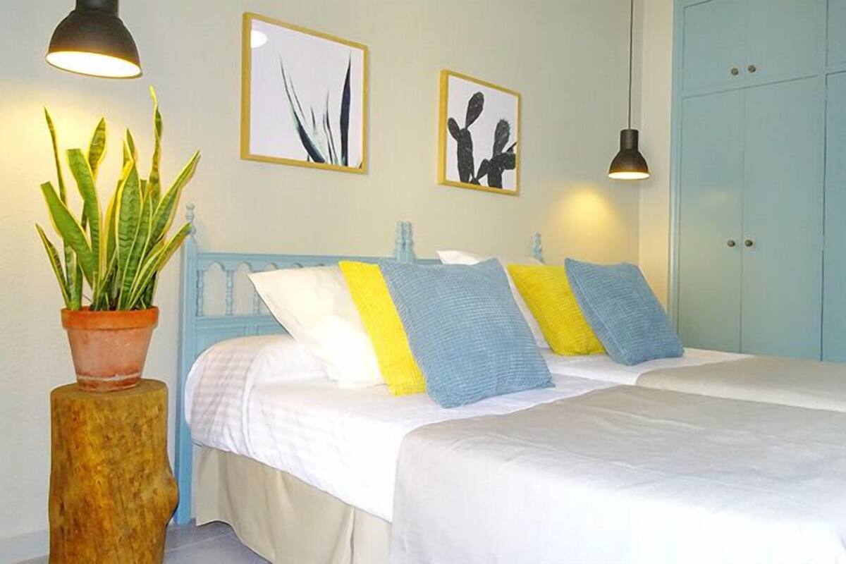 Een slaapkamer met een bed, een potplant en kunst aan de muur.