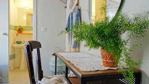 Una pequeña mesa con una planta en maceta, una silla y un mantel individual.