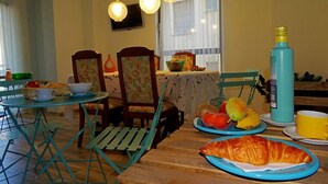 Comedor con mesa de madera, sillas y diversos alimentos, incluyendo pan y frutas.
