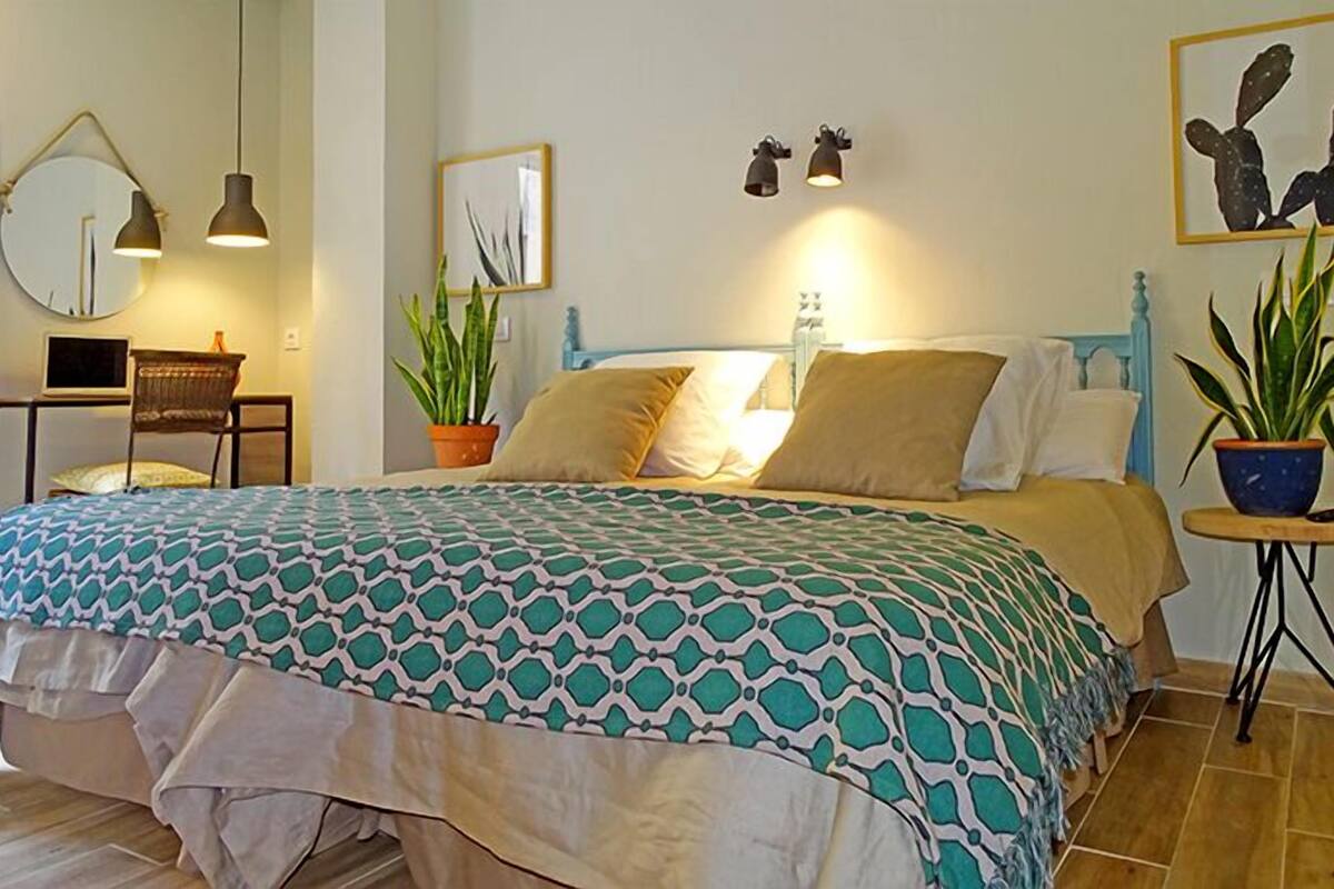 Een slaapkamer met een bed, nachtkastjes, een bureau en een stoel.