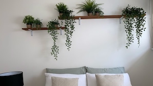 A bedroom with a bed, pillows, a lamp, and hanging plants on shelves. - McCrae beach Villa on Wattle Place, a 5 mins walk to the beach (McCrae)
