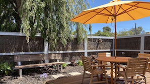 A wooden deck with a table and chairs, an umbrella, and a bench. - McCrae beach Villa on Wattle Place, a 5 mins walk to the beach (McCrae)