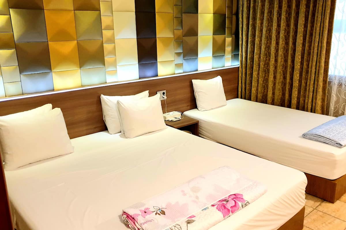 Ein Hotelzimmer mit zwei Betten, einem Holzkopfende, einem Nachttisch und einer dekorativen Wandverkleidung.