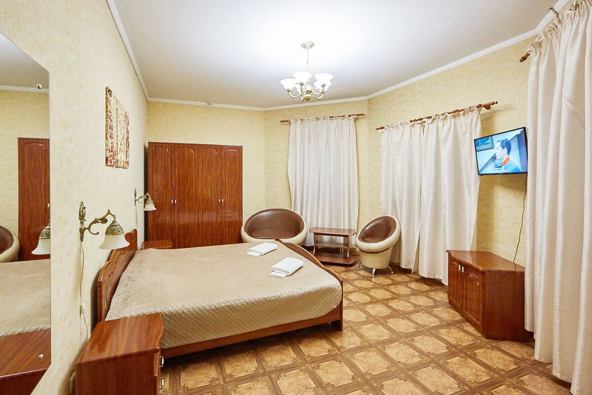 Una habitación de hotel con cama, escritorio, silla, televisor y armario.