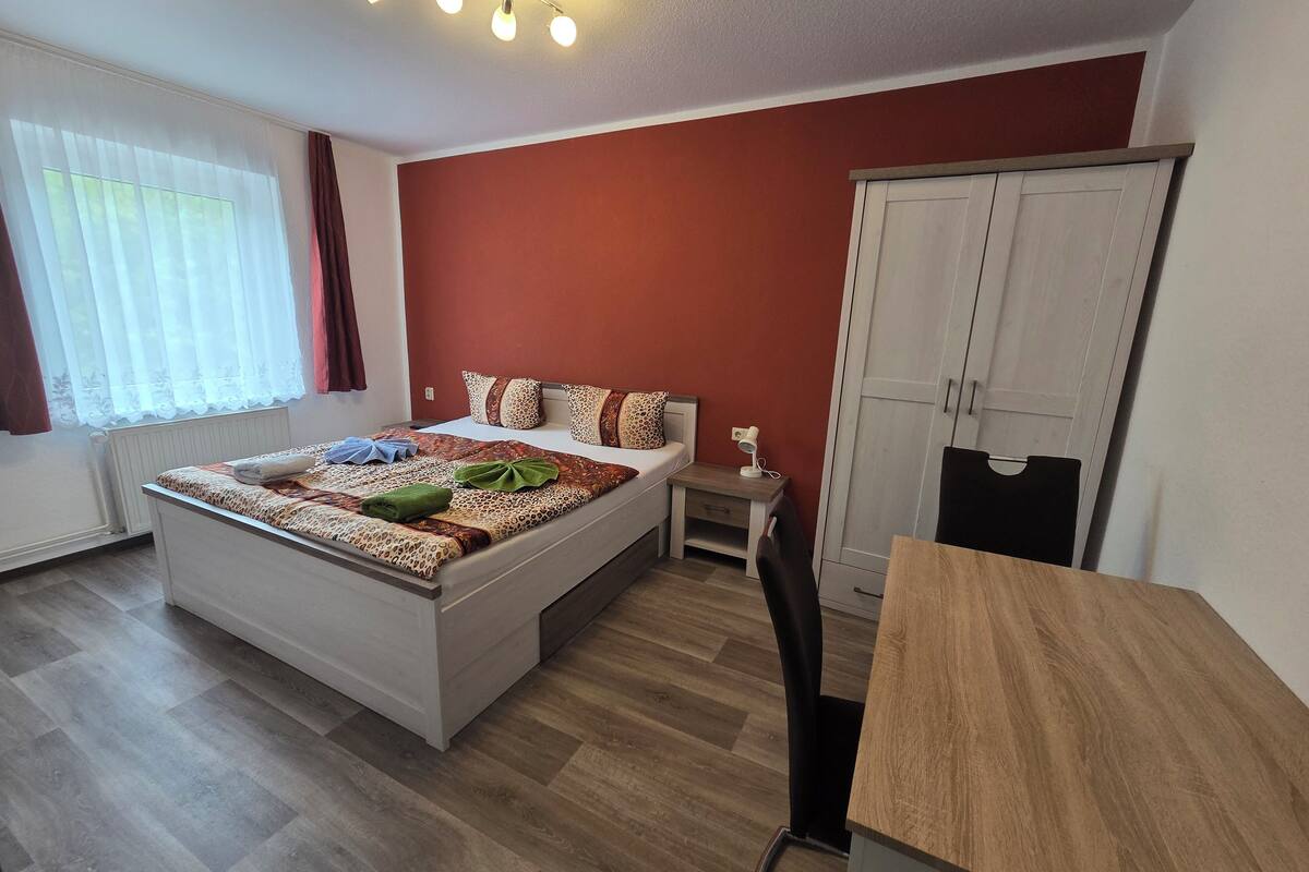 A modern bedroom with a bed, bedside table, and wardrobe.