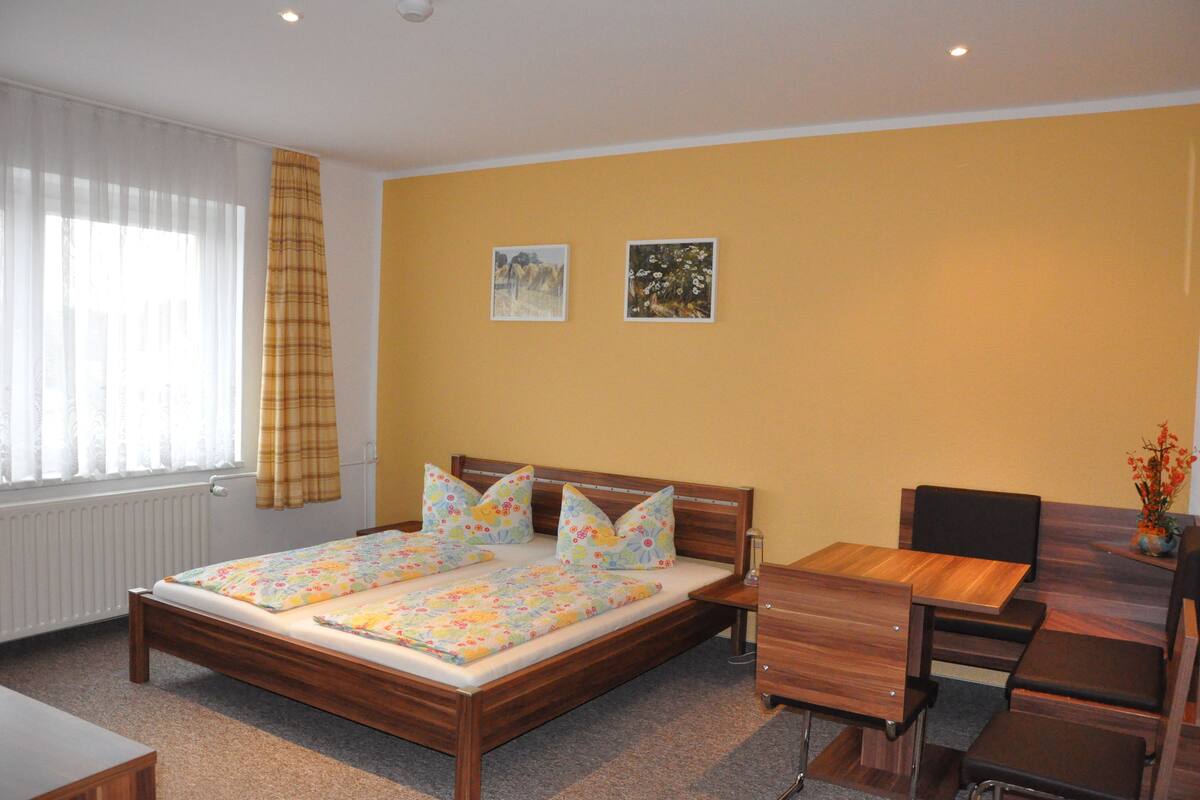 A bedroom with a wooden bed, a desk, and a chair.