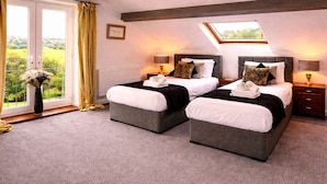 A double room with two beds, a skylight, a view of greenery, and a radiator. - Juliet Cottage - Sleeps up to 3 - Large Hot Tub (Stratford upon Avon)