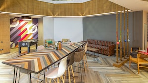 A spacious room with a long table, chairs, a sofa, and a pool table. There is a staircase leading to an upper level. - Ginger Goa Madgaon (Margao)