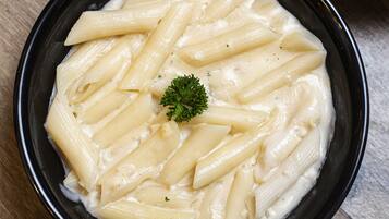 A bowl of pasta with a garnish, placed on a wooden surface.