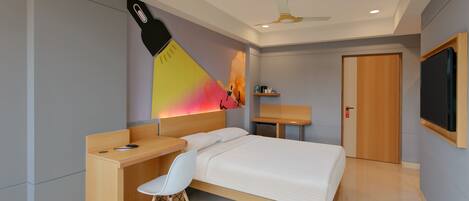 Una habitación de hotel moderna con cama, escritorio, silla y televisor.