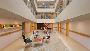A spacious lobby with a high ceiling, modern furniture, and a central seating area. - Ginger Goa Madgaon (Margao)