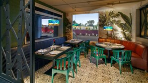 A restaurant interior with booths, green chairs, and a patterned floor. - Ginger Goa Madgaon (Margao)