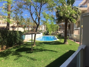 A swimming pool surrounded by greenery, a thatched structure, and a sign reading "GRACIAS EL PAN". - PUERTA PALMAR H2 (Denia)
