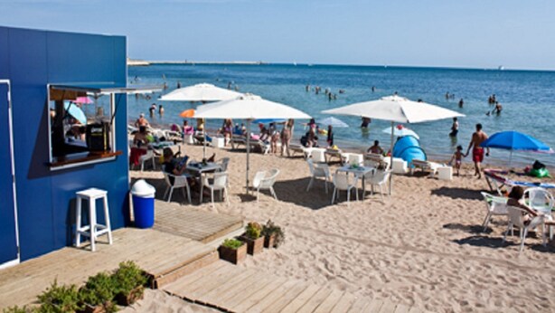 Un restaurant a la vora de la platja amb terrassa, ombrel·les i vistes al mar.