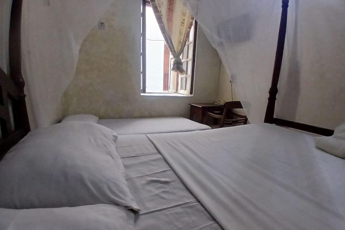 A room with two beds, a window, and a desk.