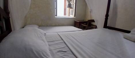 A room with two beds, a small table, and a window with curtains.