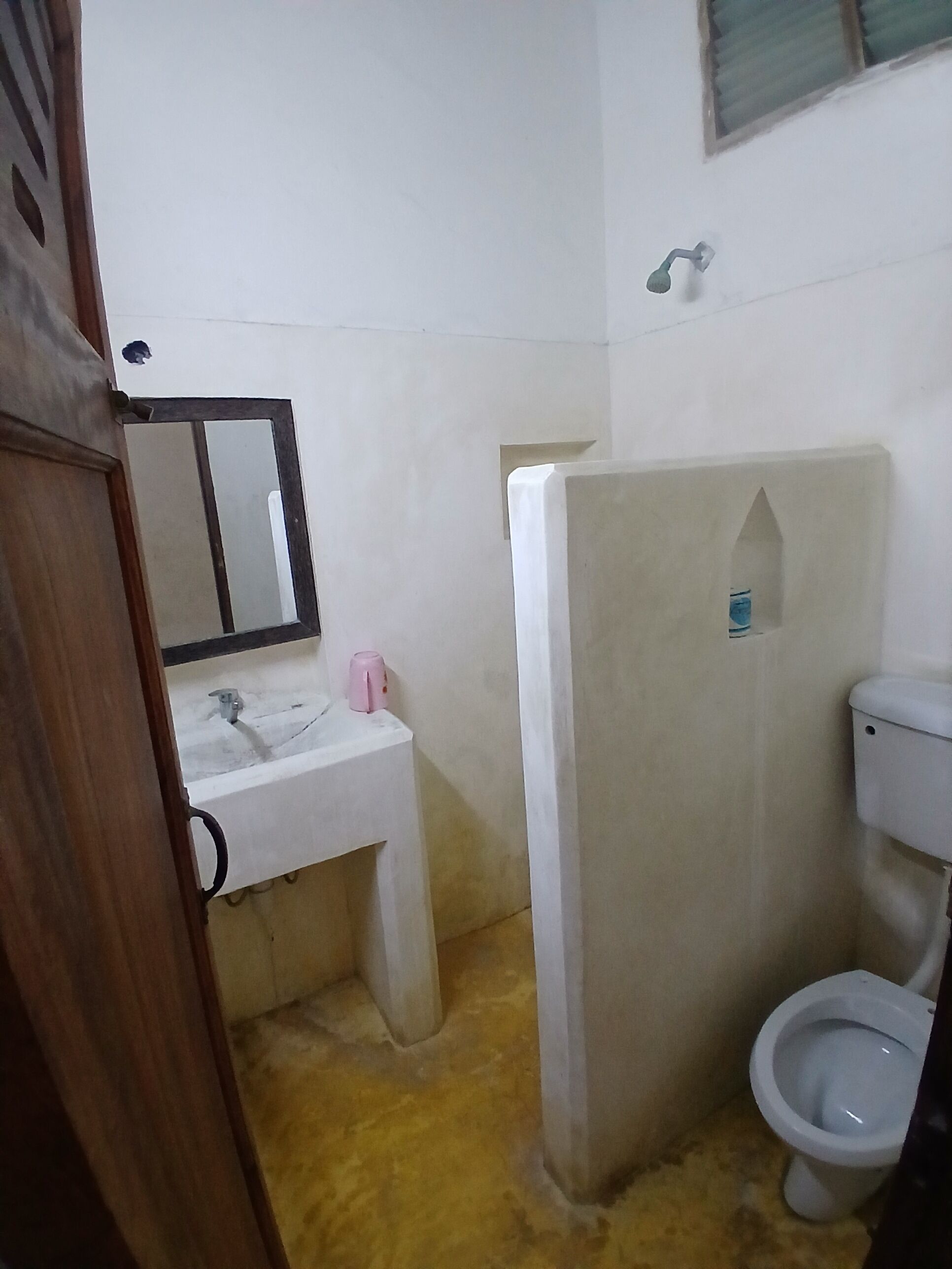 A bathroom with a sink, mirror, toilet, and shower area.
