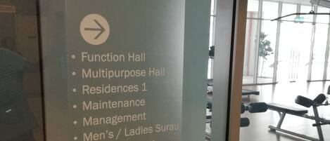 A sign listing various amenities including a swimming pool, hydro gym, jacuzzi, playground, function hall, multipurpose hall, residences, maintenance, management, men's and ladies sauna, and steam room.