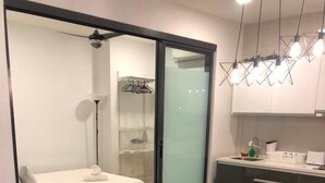 Um espaço de estar compacto com sofá, cama, mesa pequena e cozinha compacta.