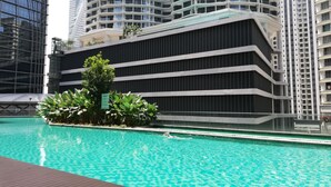 Um edifício moderno com piscina, rodeado por arranha-céus.