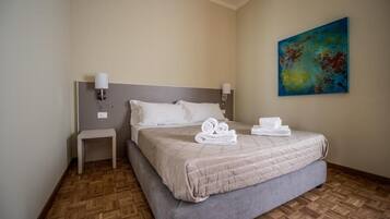 A hotel room with a large bed, a bedside table, and a painting on the wall.