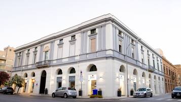 Um edifício histórico com fachada clássica, janelas em arco e entrada central.
