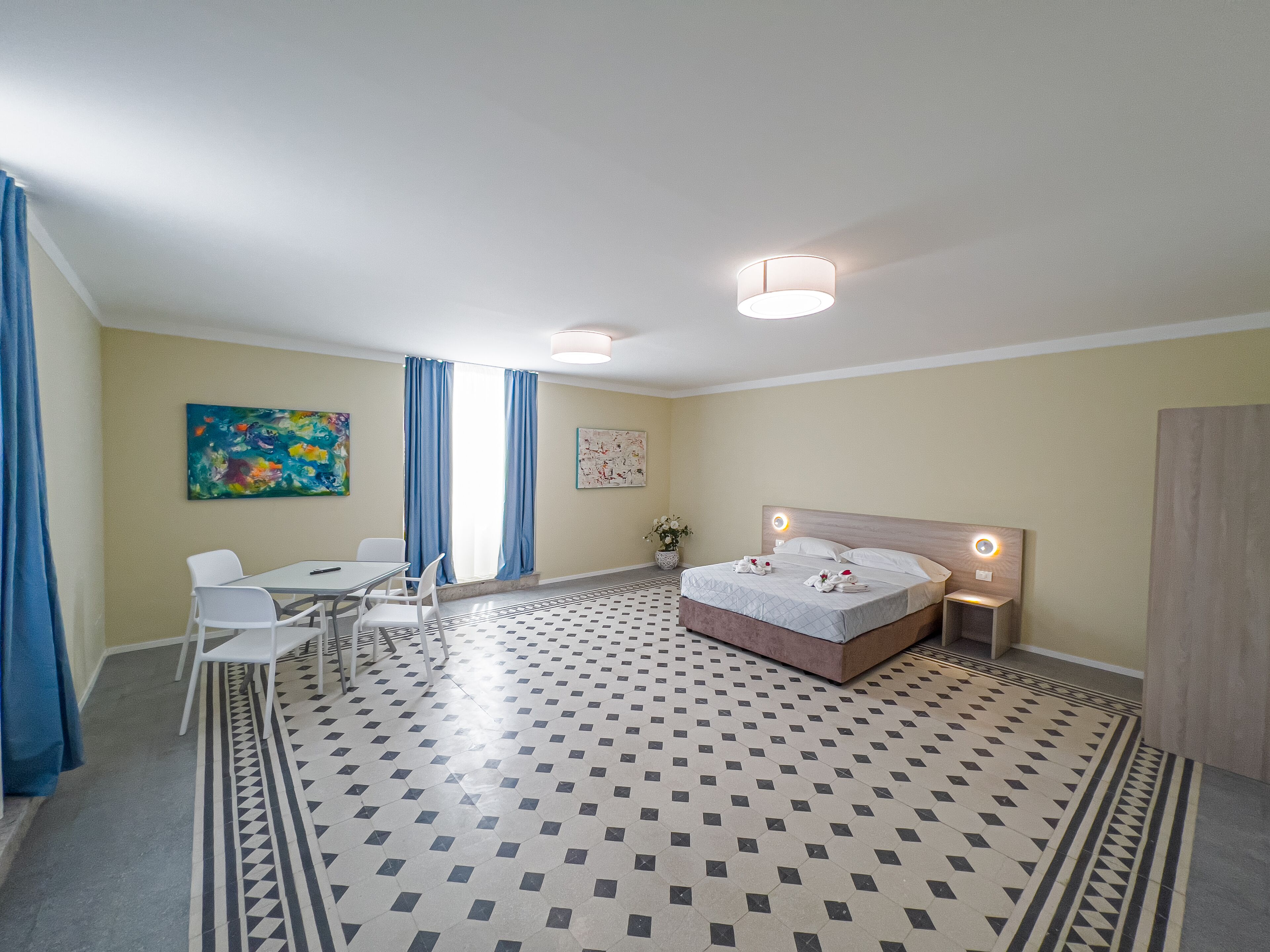 Una habitación de hotel con una cama, un escritorio, una silla, un cuadro y suelo con estampado.
