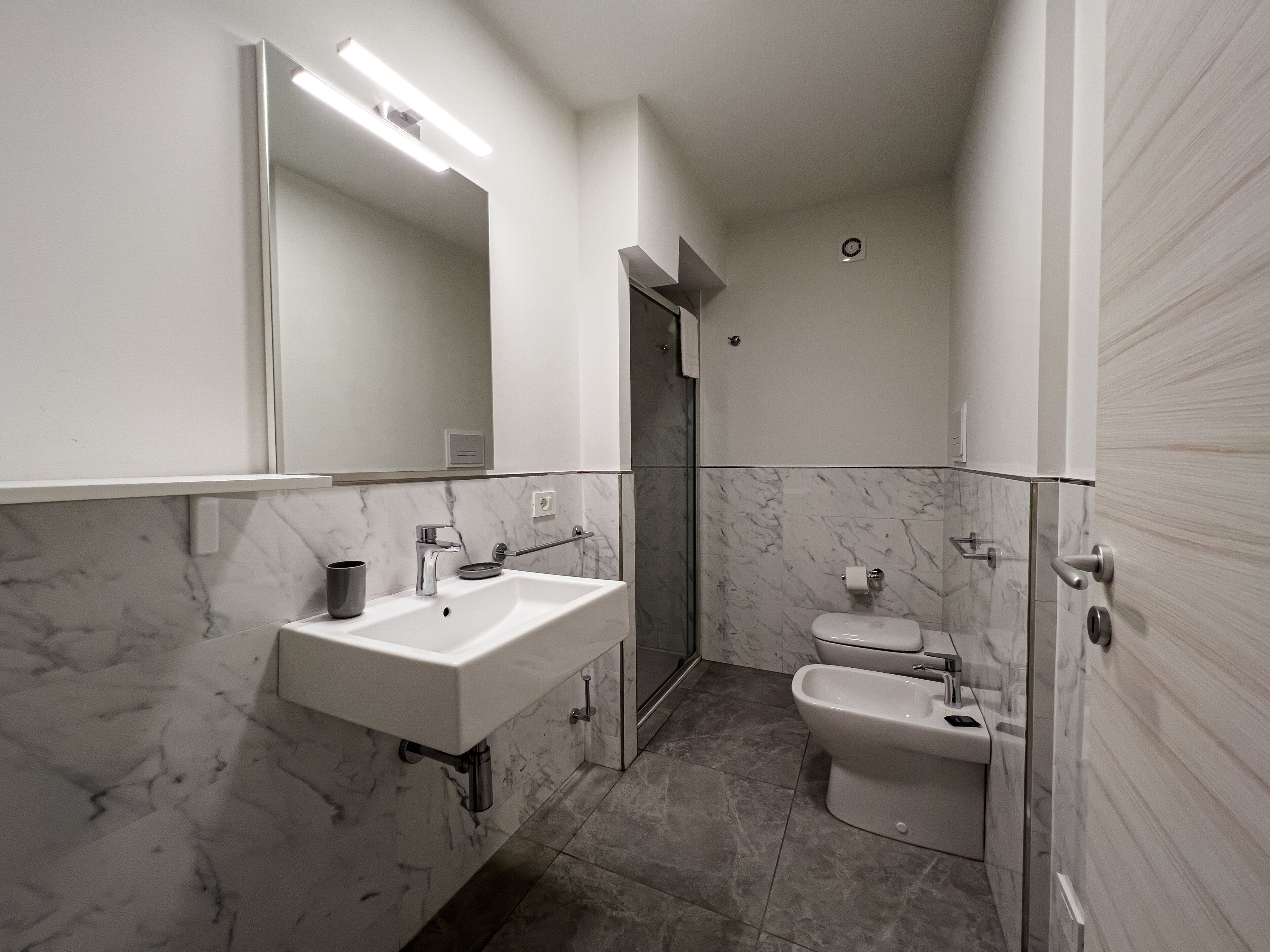 A modern bathroom with a white sink, a bidet, and a toilet.