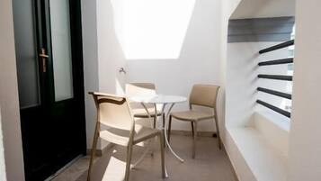 A narrow outdoor space with a table and chairs, a door, and a staircase.